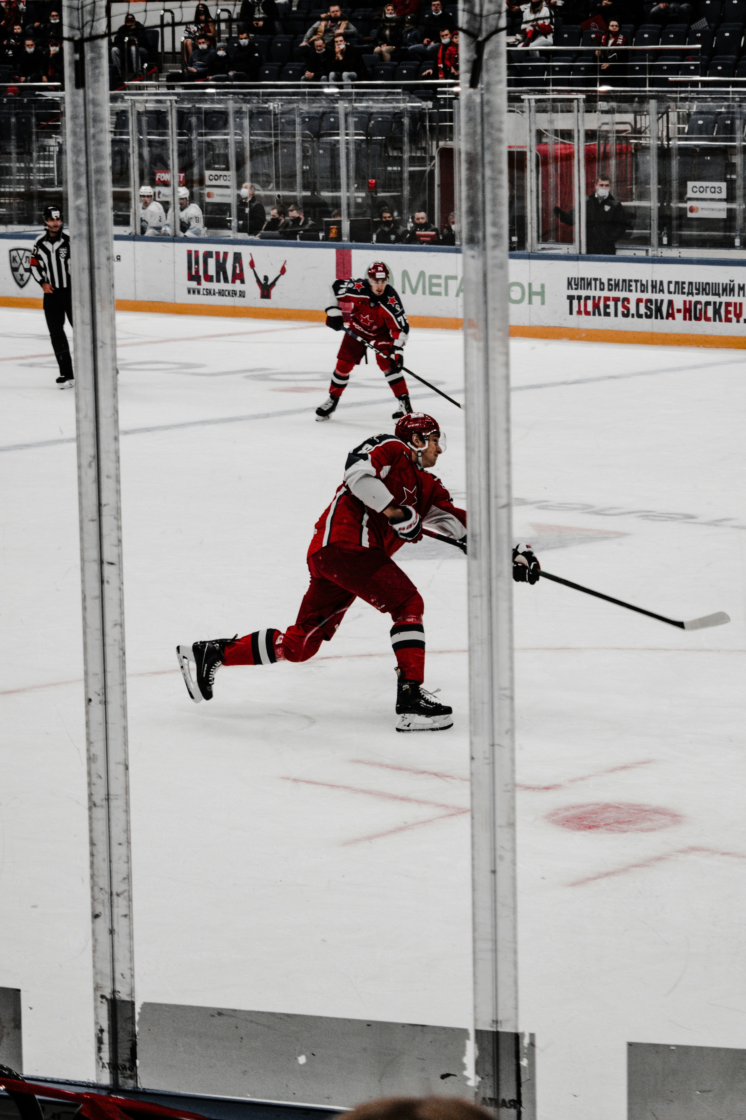 man in red ice hockey jersey playing ice hockey